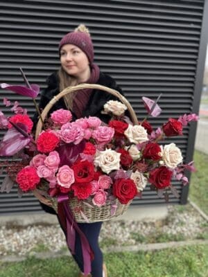 Woman outdoors holding a large basket filled with assorted colorful roses.